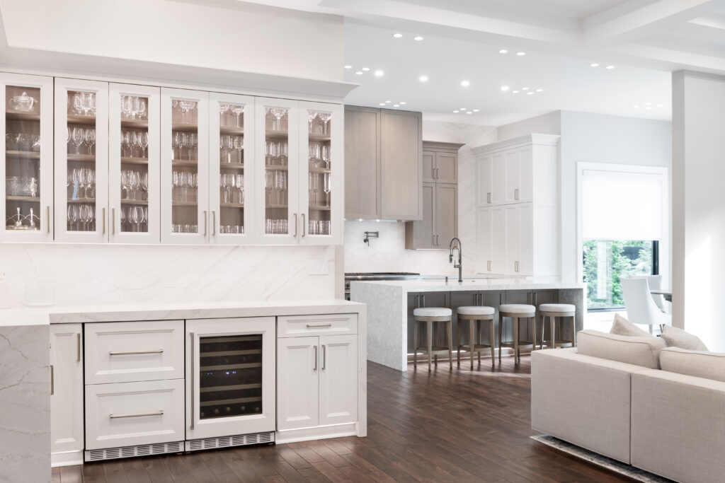 Bright open kitchen renovation featuring glass display cabinets, marble countertops, and a spacious island with seating.
